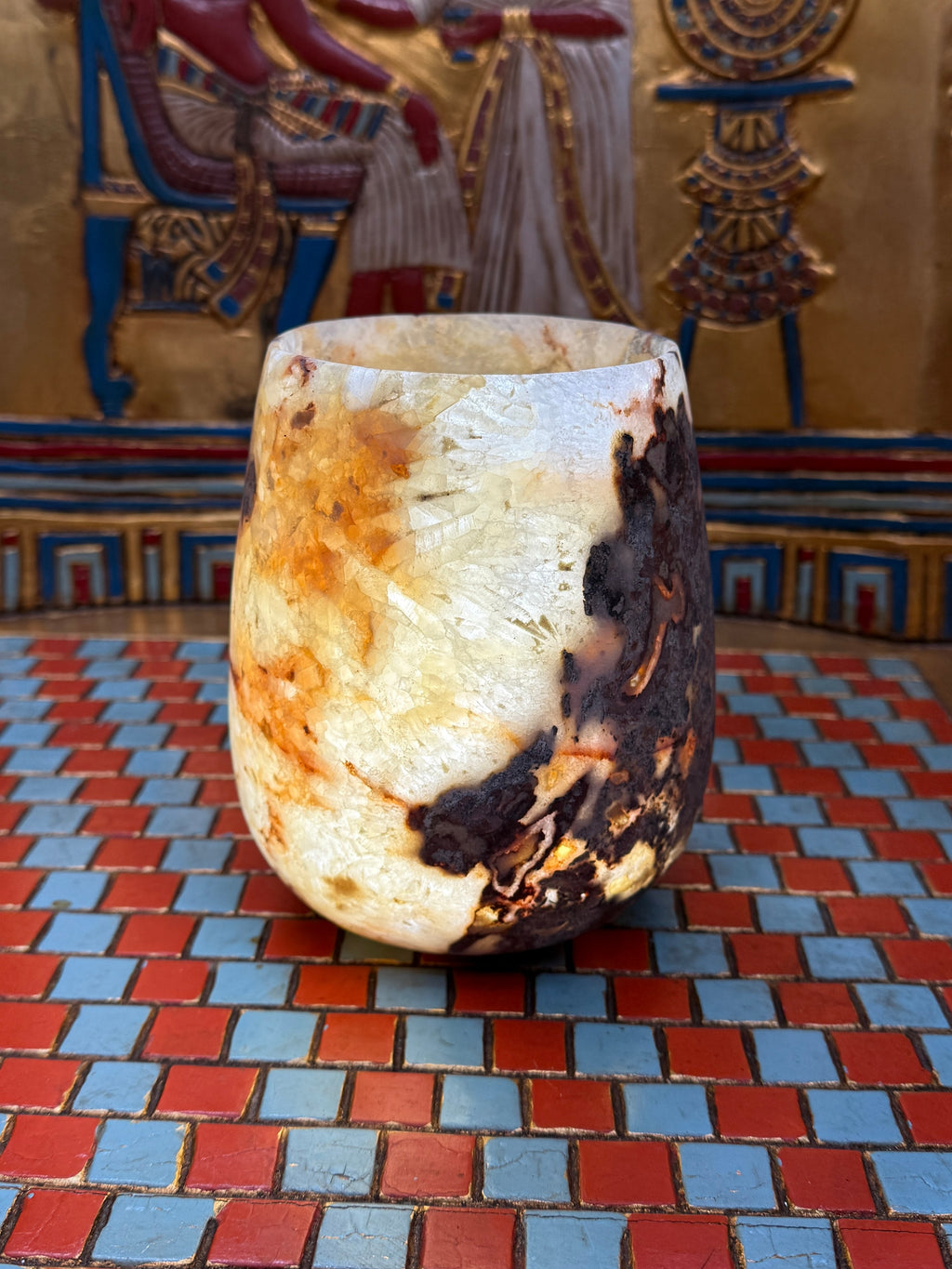 Compact curved alabaster vase with cream and taupe stone and contrasting brown markings — illuminated view.