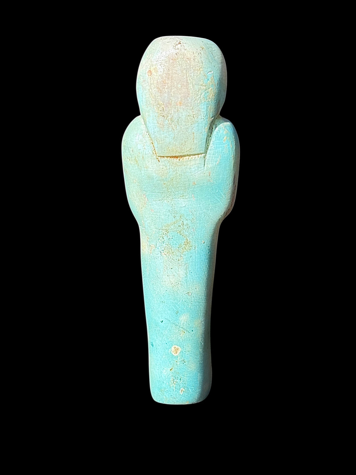 Back of turquoise-coloured stone shabti showing the outlined headdress, tapered body and pale cream and tan surface patches.