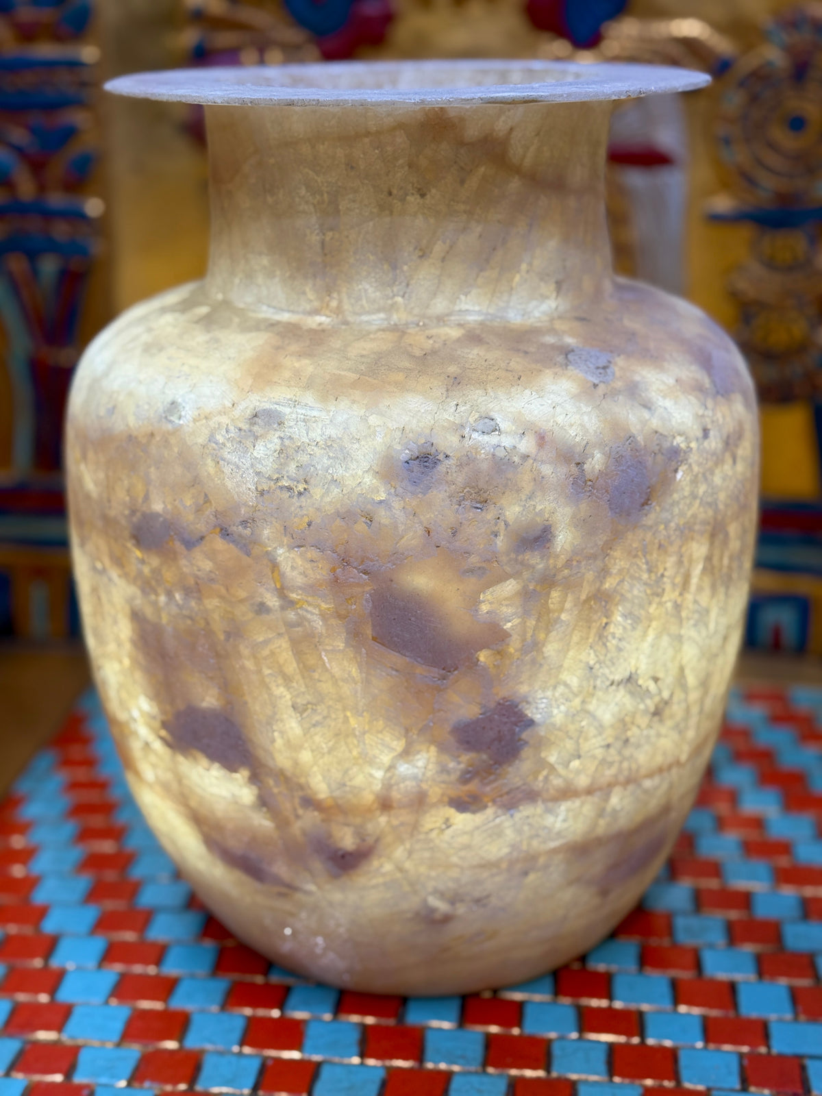 Large cream and sandy taupe alabaster vase with broad shoulders, a straight neck and flared rim — illuminated view.