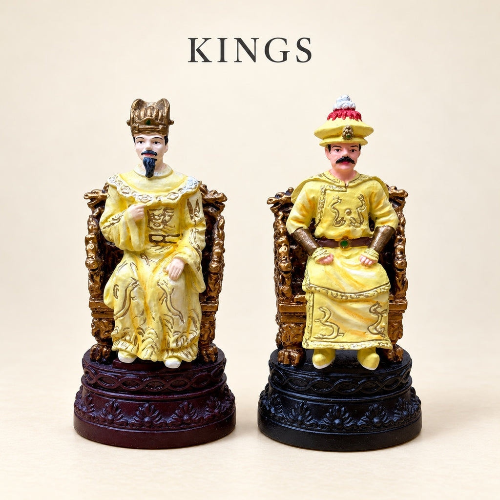 Two Chinese Dynasties pewter king pieces seated in gold-coloured robes on dark red and black decorative bases.