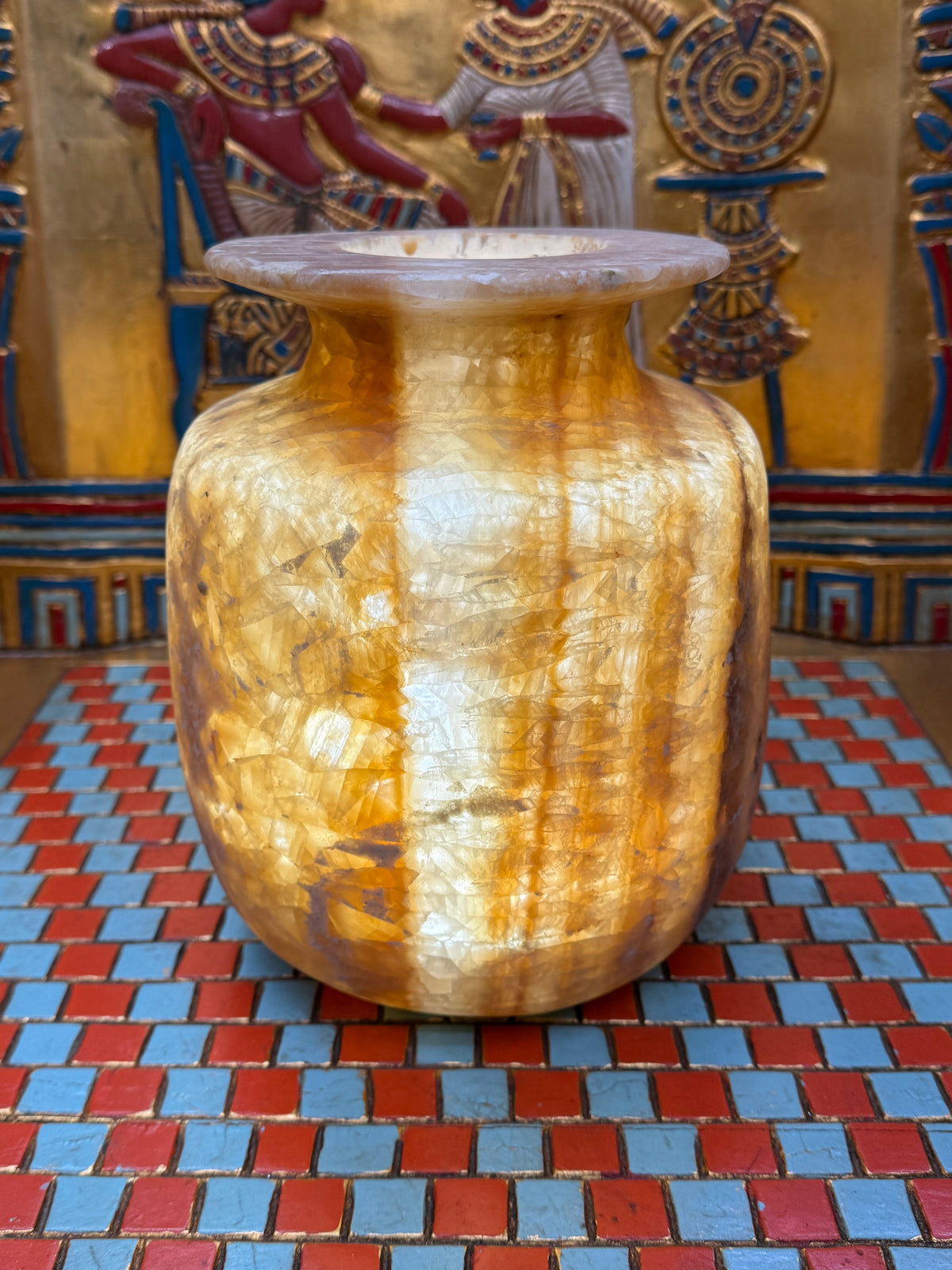 Broad alabaster vase with caramel and cream bands, rounded shoulders and a wide flared rim — illuminated view.