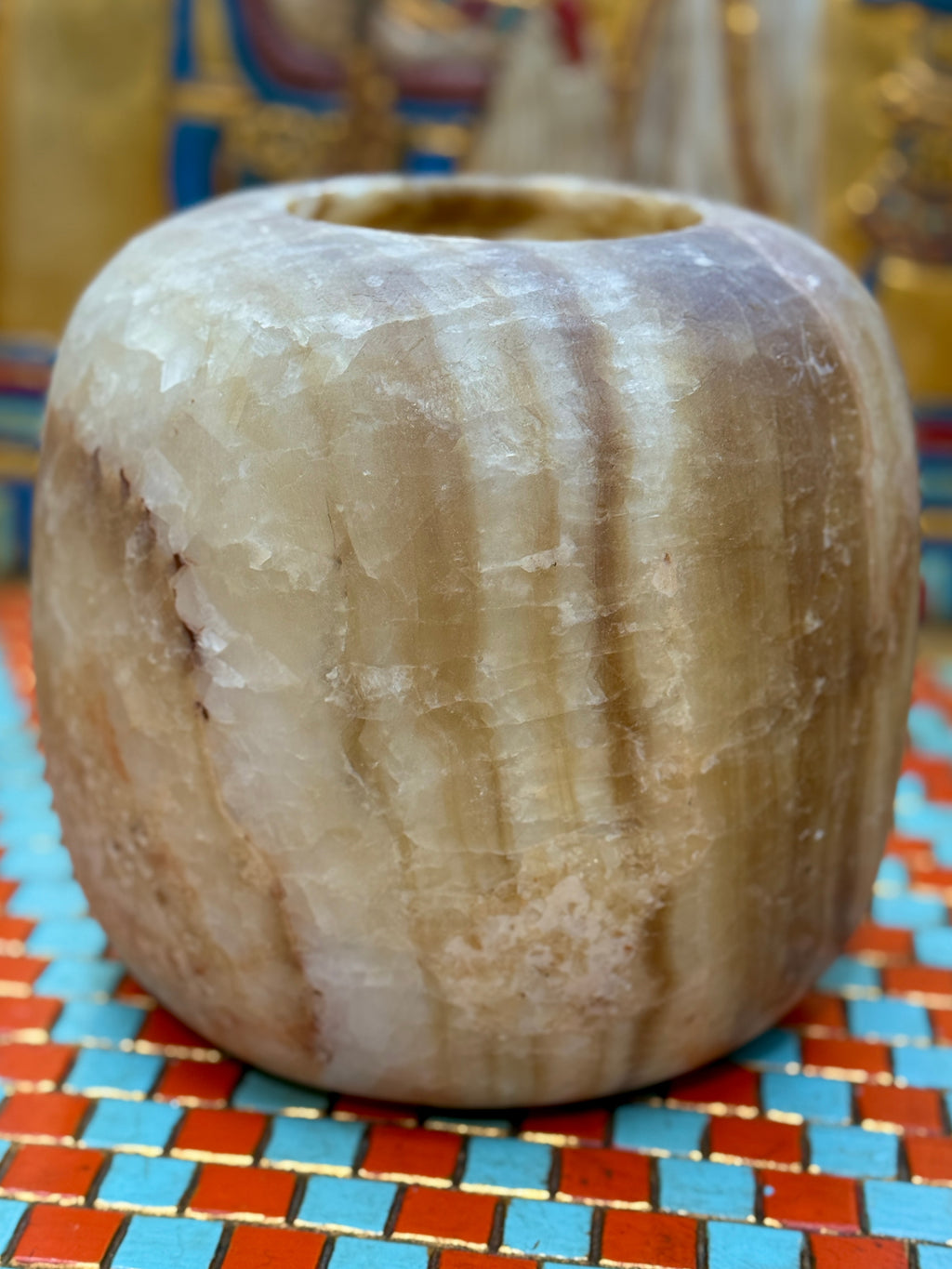 Broad cream alabaster vase with rounded shoulders, golden-brown vertical bands and a simple opening — unlit full view.