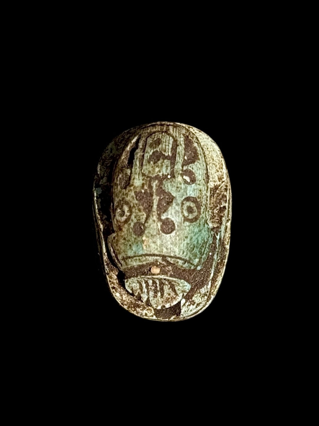 Top view of Egyptian scarab SC-112, showing dark brown and blue-green tones with markings across the upper surface.