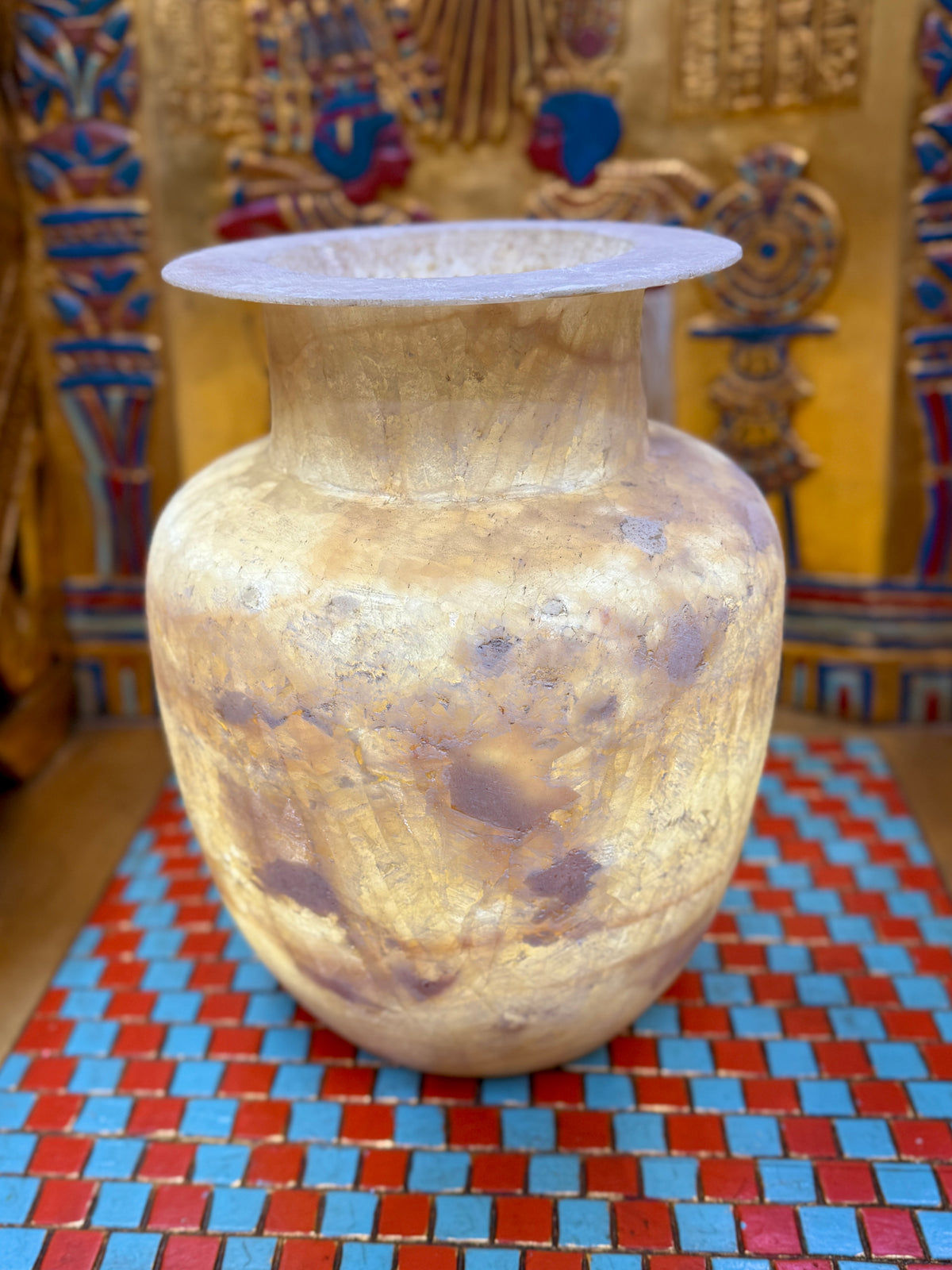 Large cream and sandy taupe alabaster vase with broad shoulders, a straight neck and flared rim — illuminated view.