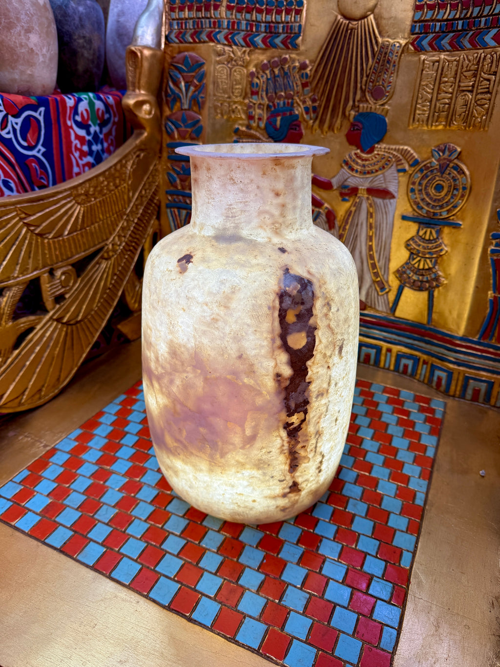 Tall alabaster vase with rounded shoulders, a flared rim and bold rust-brown markings on cream stone — full view.