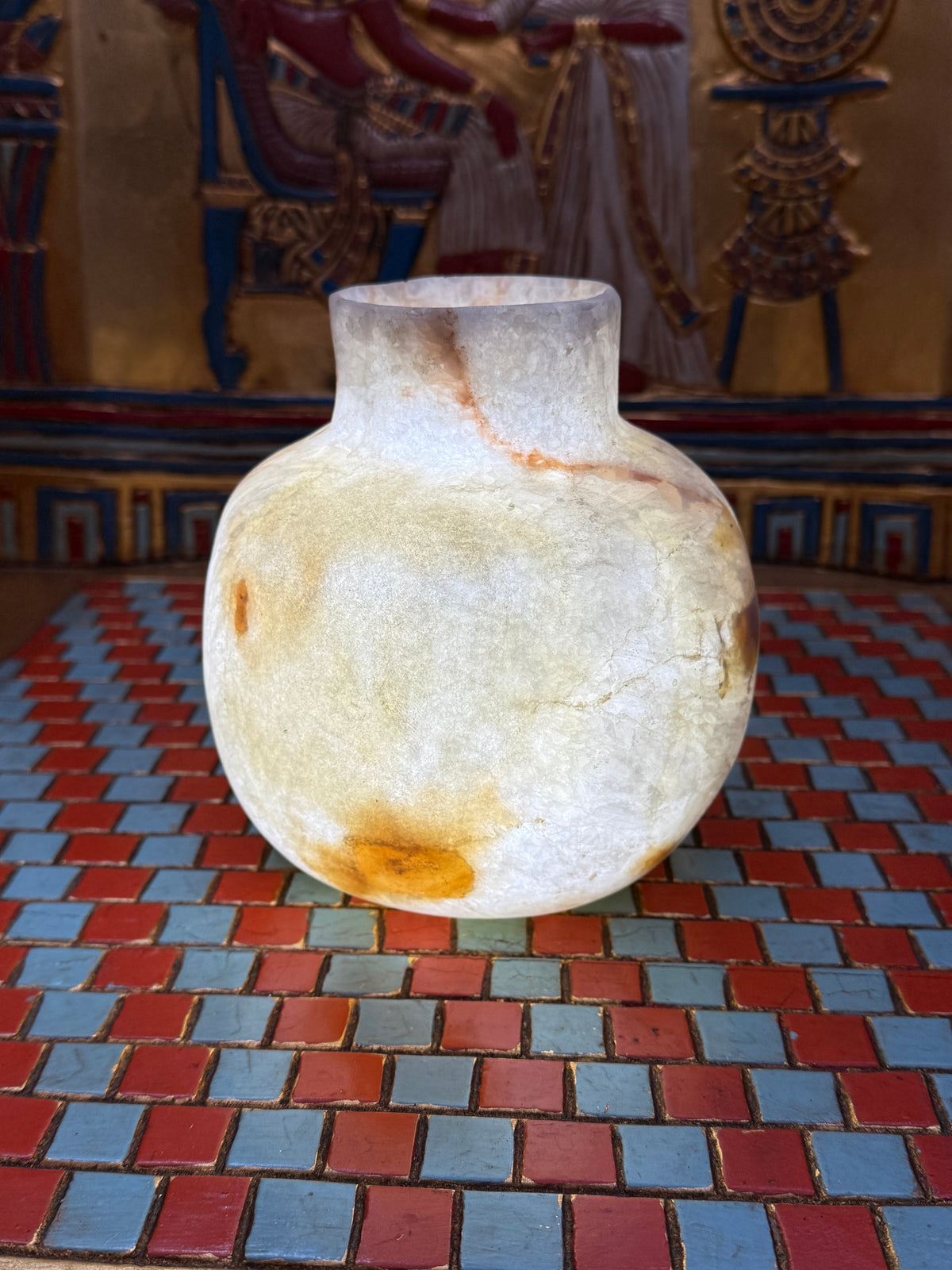 Rounded cream alabaster vase with a short straight neck, delicate warm veins and honey-coloured patches — illuminated view.