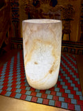 Slender cream alabaster cylinder vase with a rounded base and sweeping honey-coloured vein — full view.