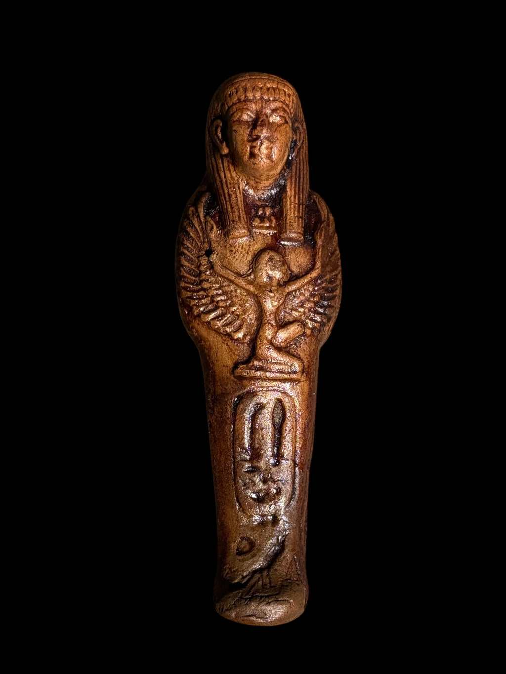 Front view of a warm brown Egyptian stone figurine with a striped headdress, winged Isis motif, oval enclosure of markings and bird motif.