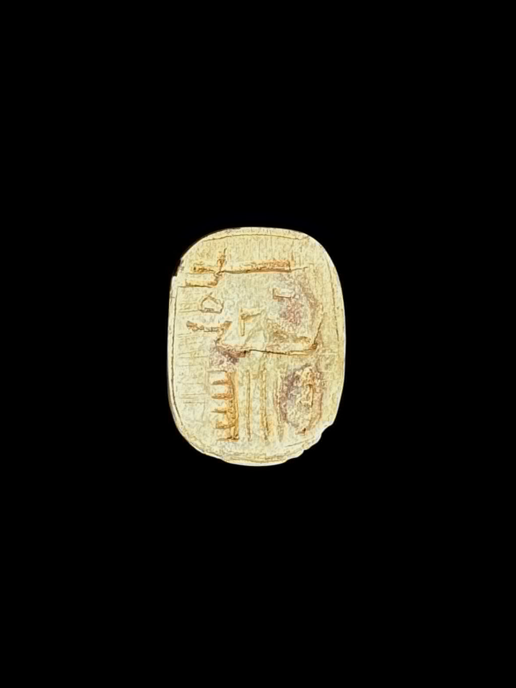Underside of a pale cream and tan stone scarab showing incised markings within an oval border against a black background.