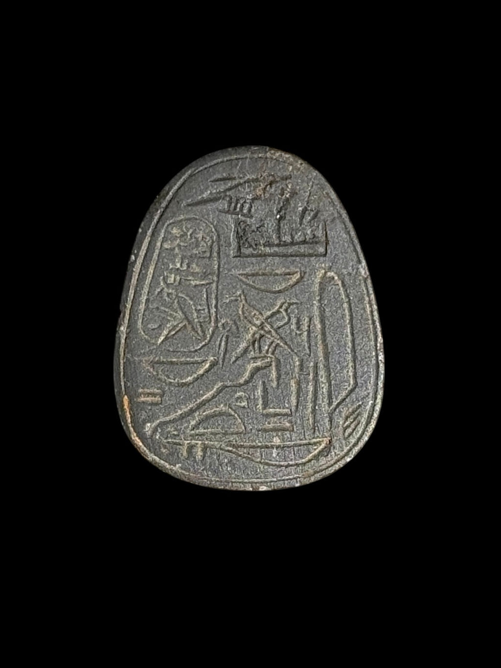 Reverse of the dark grey stone scarab, showing incised Egyptian-style markings arranged within an outlined border.