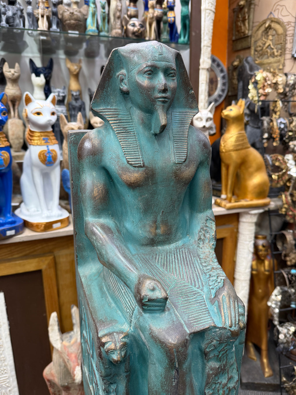 Close front view of Khafre, showing his face, headdress, torso, pleated kilt and a lion head on the throne.