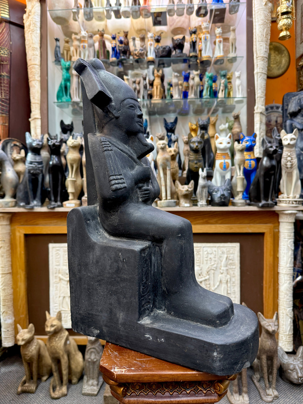 Angled side view of seated Osiris showing the projecting beard, crown, throne, rear support and extended base.