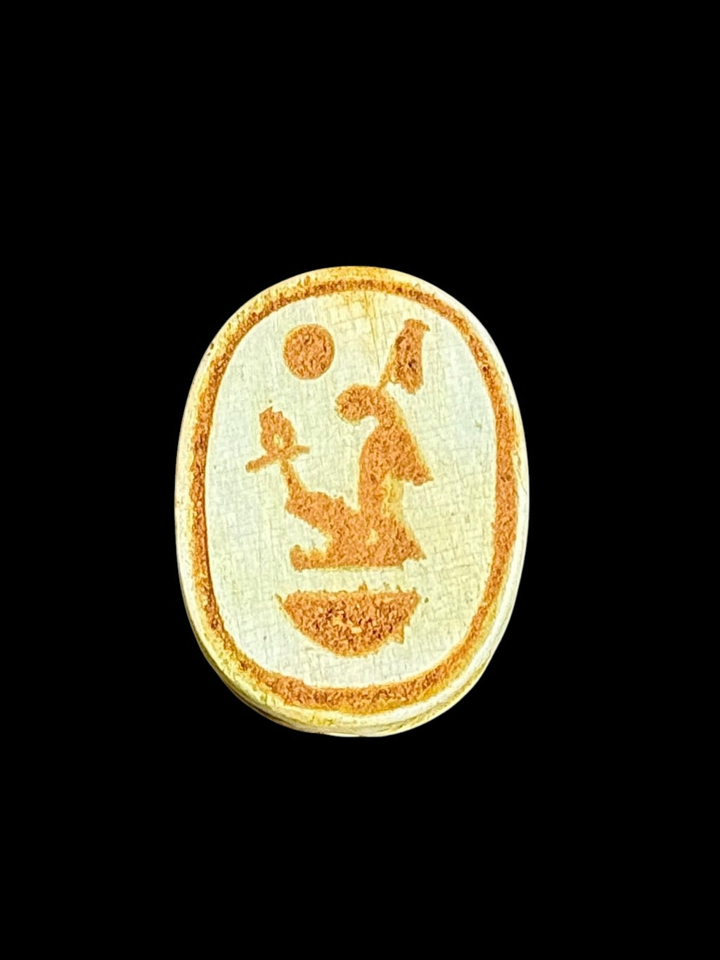 Underside of Egyptian scarab SC-101, showing pale underside with ochre figures and a curved motif.