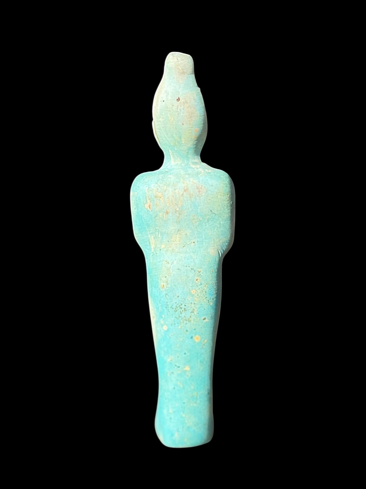 Rear view of the shabti showing its tall crown, rounded shoulders and plain tapered back with mottled turquoise and cream colouring.