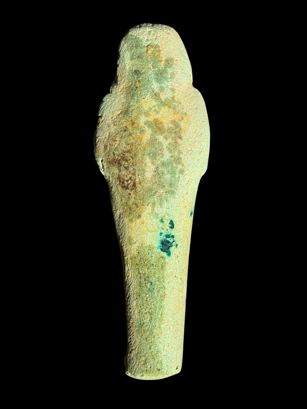 Back view of the shabti figurine showing a mostly plain, rounded surface with pale green, ochre and darker green patches.
