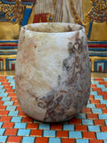 Compact curved alabaster vase with cream and taupe stone and contrasting brown markings — unlit full view.