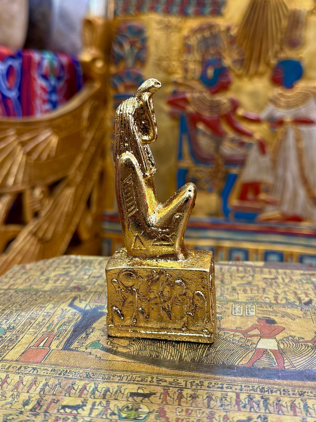Side view of the gold finish Meretseger kneeling statue with cobra head and decorated square base.