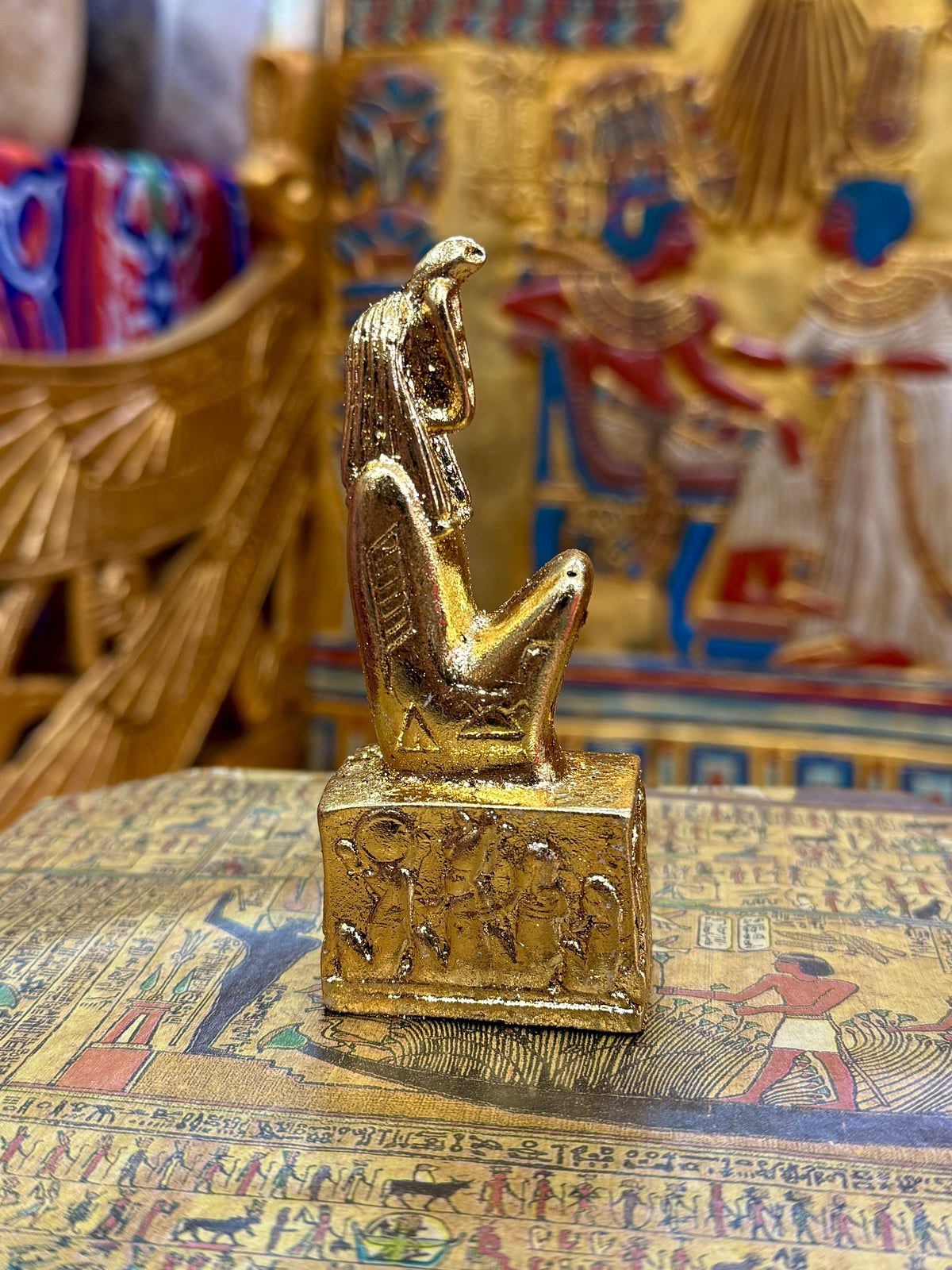 Side view of the gold finish Meretseger kneeling statue with cobra head and decorated square base.