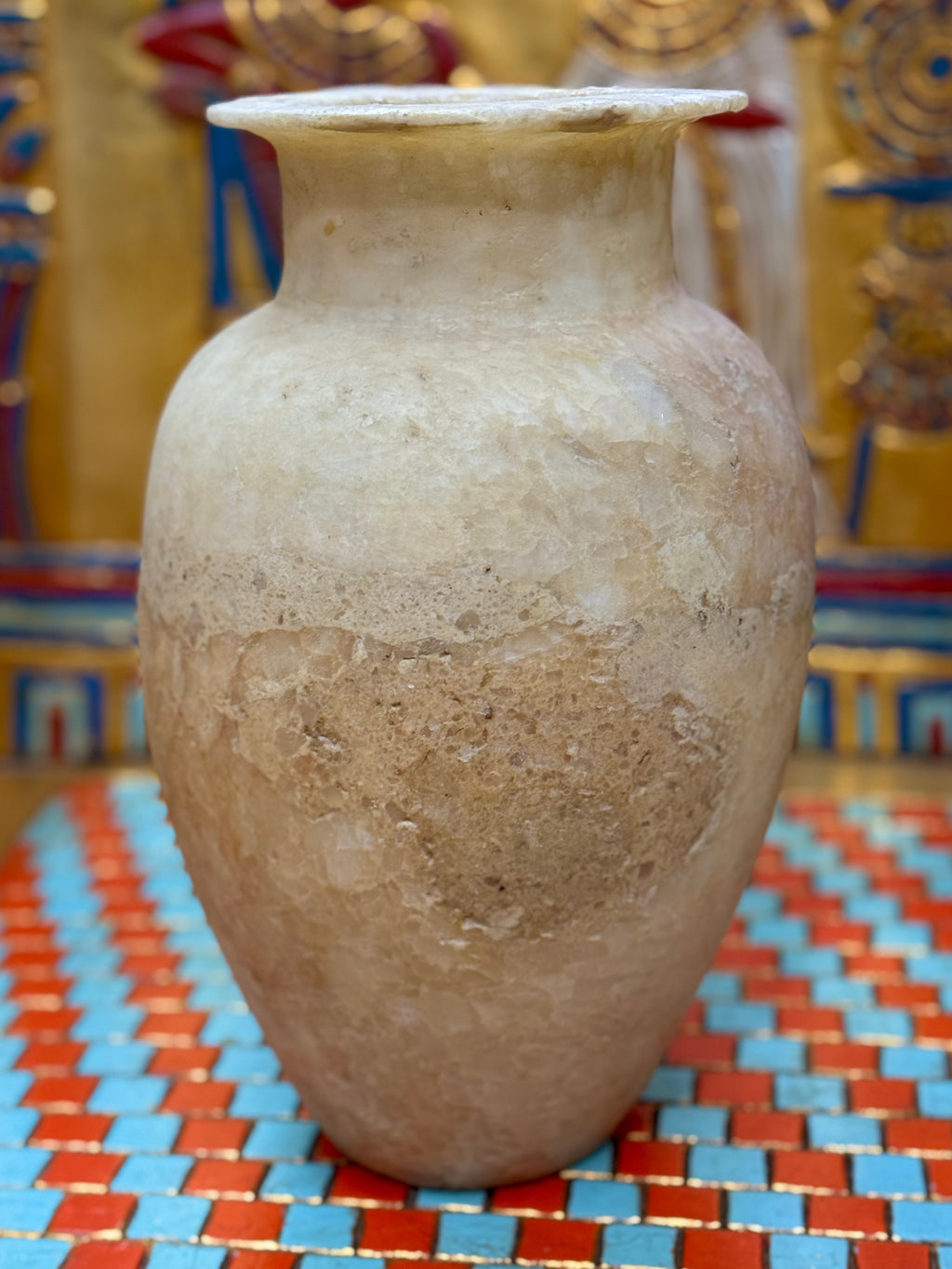 Alabaster vase with a pale upper body, broad earthy band, rounded shoulders and flared neck — unlit full view.