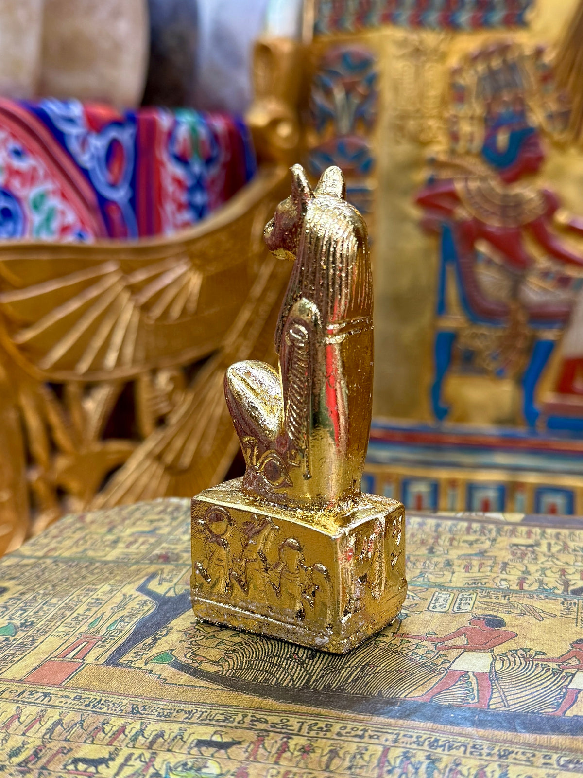 Rear view of the gold finish Bastet kneeling statue, showing the headdress and decorated base.