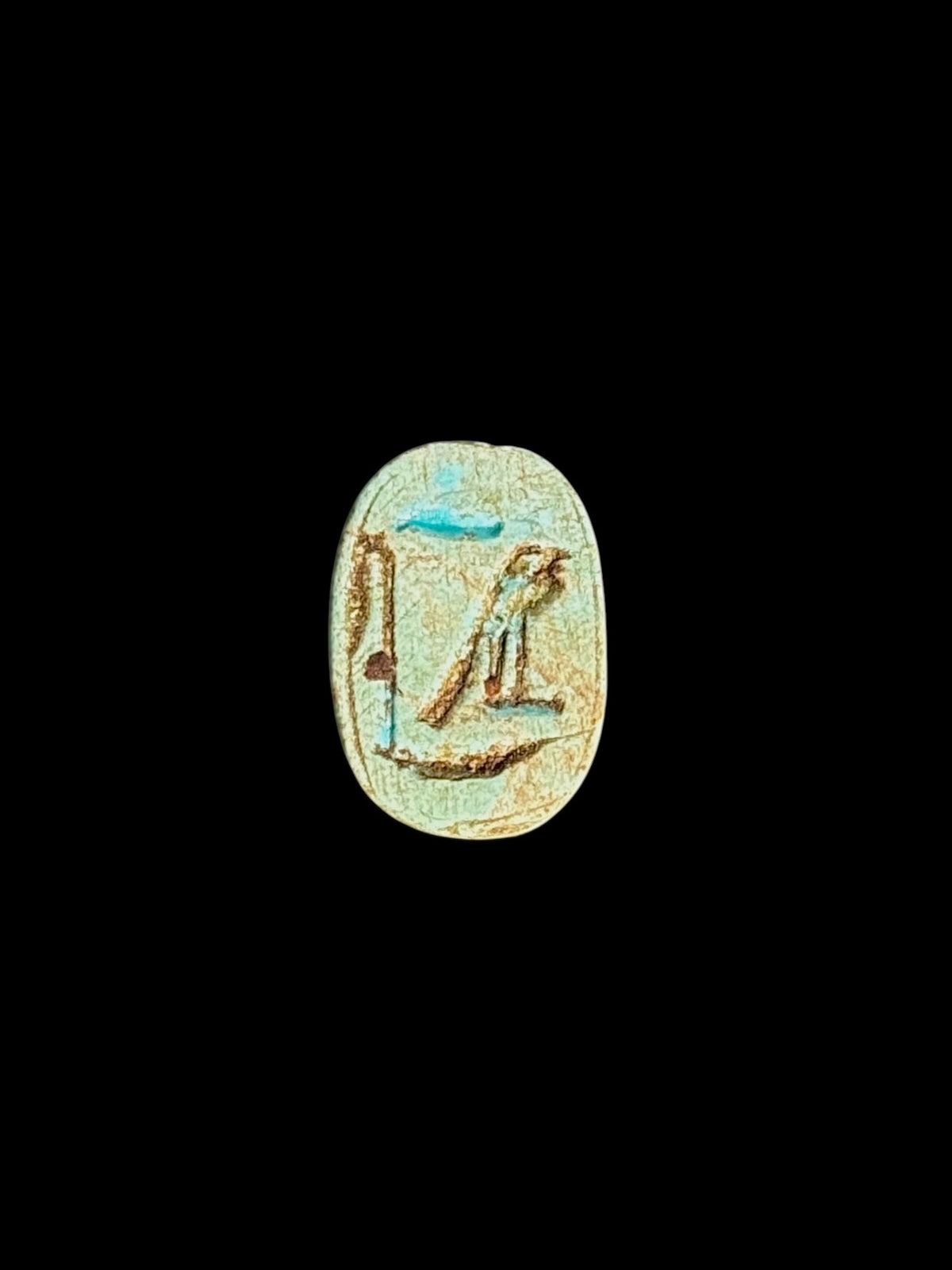 Pale cream-green oval underside of a stone scarab with incised markings, brown accents and turquoise patches against a black background.