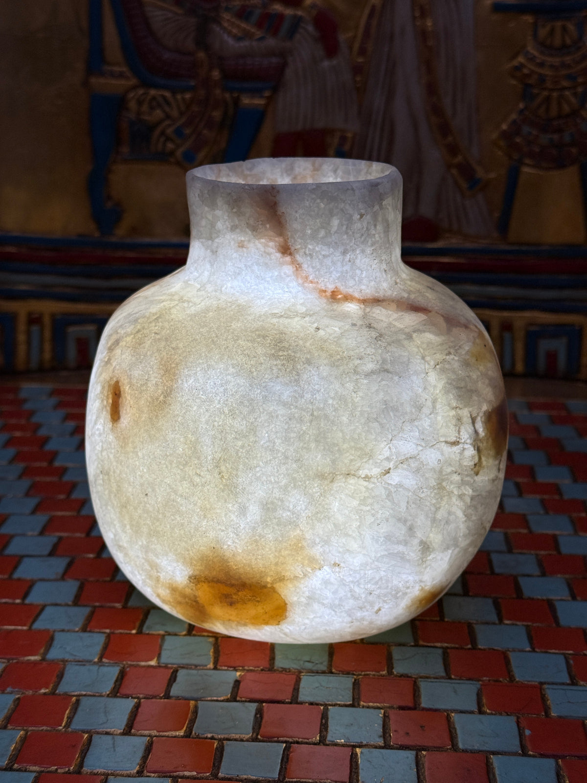 Rounded cream alabaster vase with a short straight neck, delicate warm veins and honey-coloured patches — illuminated view.