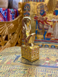 Front angled view of the gold finish Horus kneeling statue with falcon head and decorated square base.
