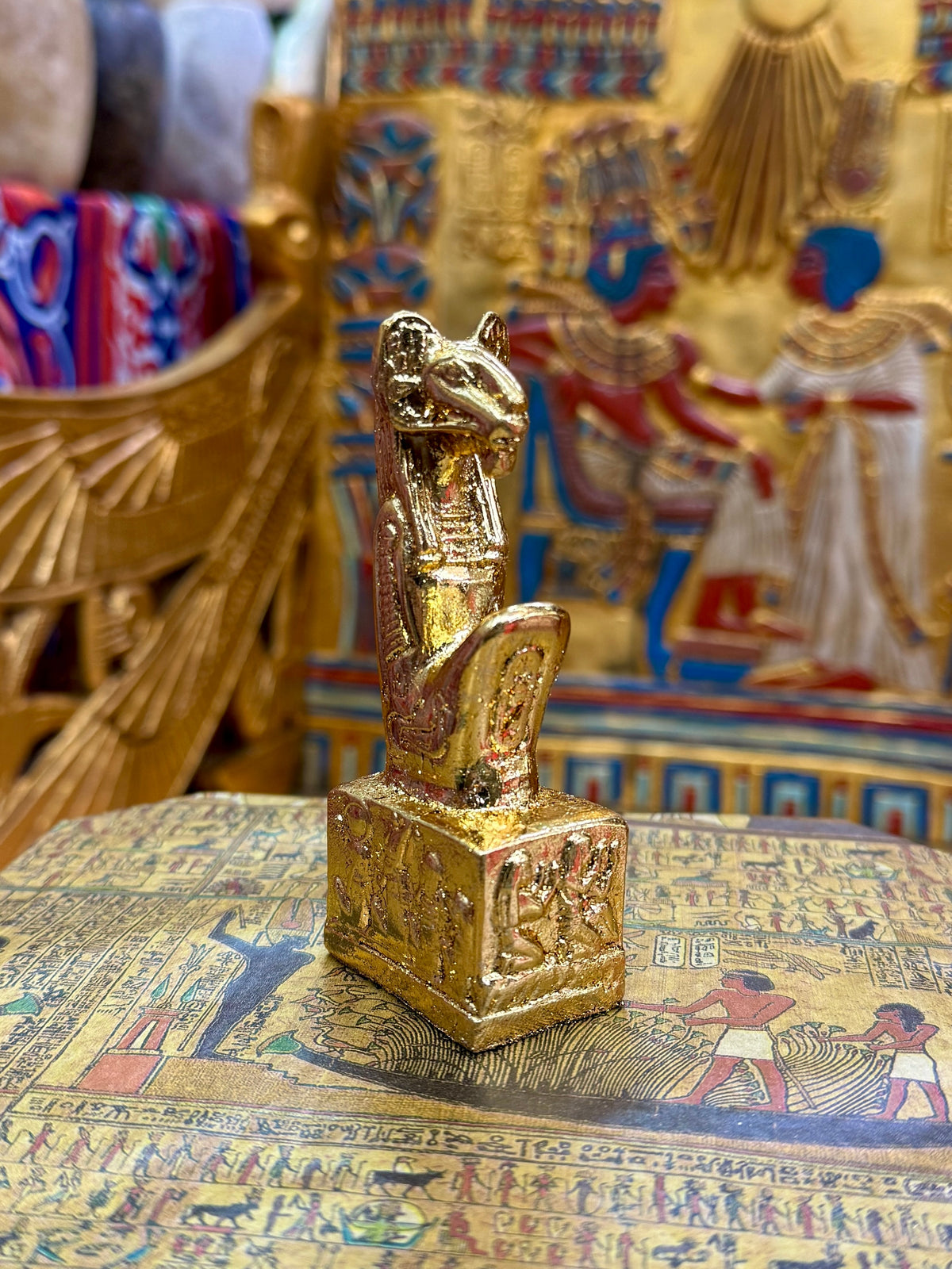 Front angled view of the gold finish Khnum kneeling statue with ram head, sculpted headdress and decorated square base.