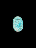 Oval underside of a turquoise-coloured stone scarab with incised markings, a recessed border and pale surface mottling.