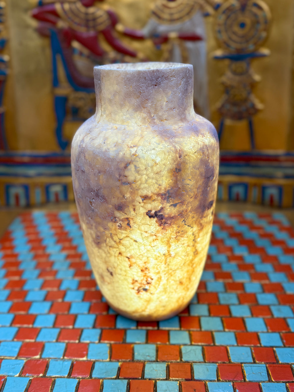 Slender smoky taupe and cream alabaster vase with rounded shoulders and a straight neck — illuminated view.