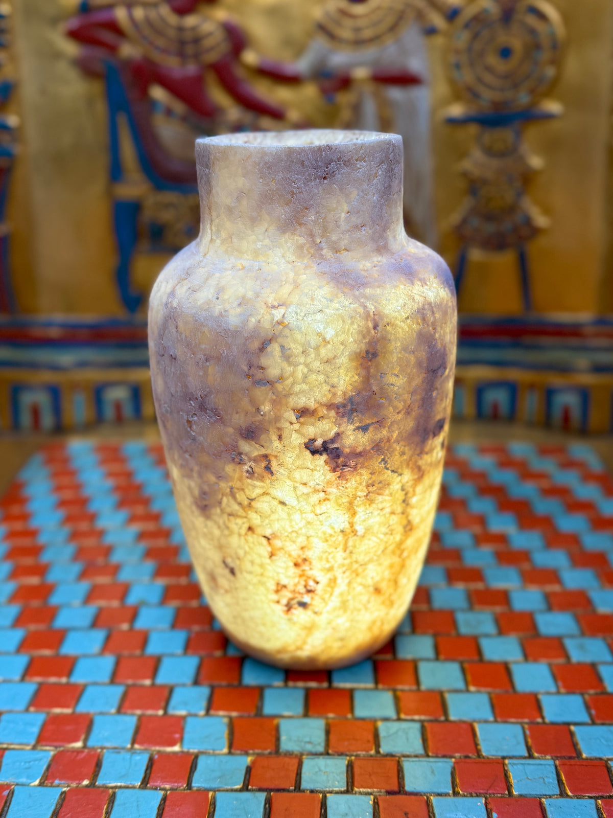 Slender smoky taupe and cream alabaster vase with rounded shoulders and a straight neck — illuminated view.
