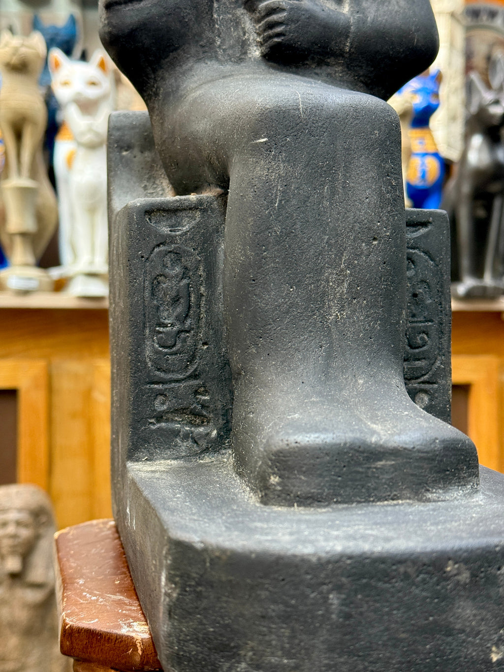 Detail of the statue's lower body and base, with incised hieroglyphic markings on the throne beside the legs.