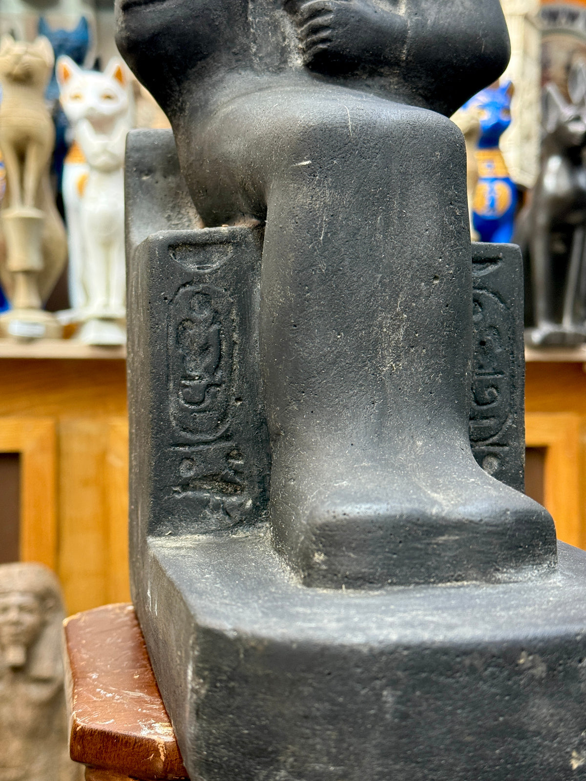 Detail of the statue's lower body and base, with incised hieroglyphic markings on the throne beside the legs.