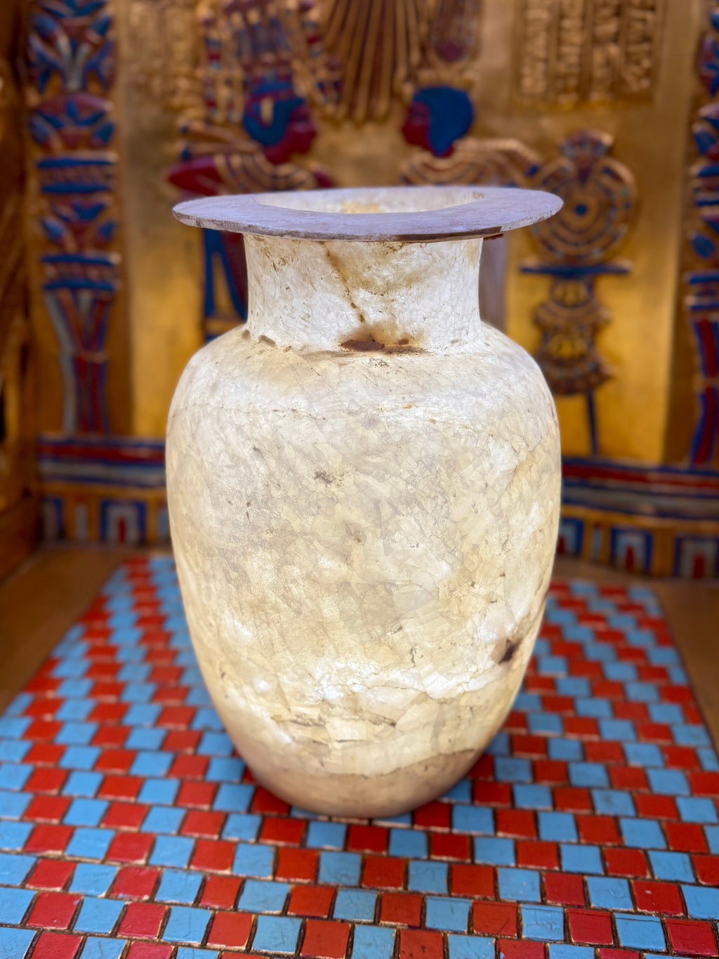 Tall pale alabaster vase with branching brown veins, an upright neck and flared rim — full view.