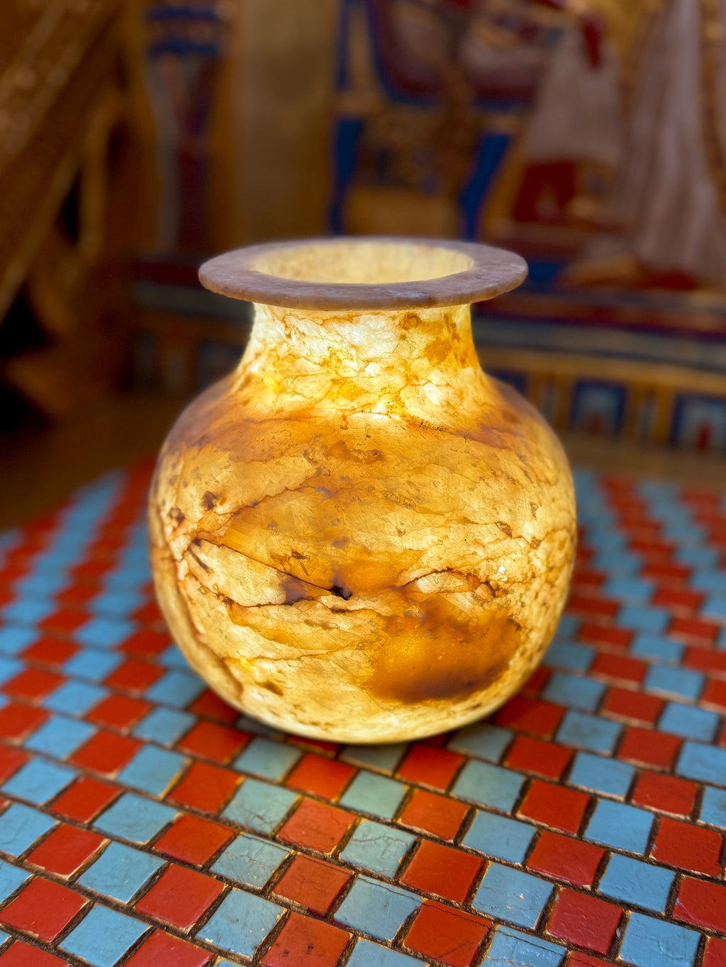 Small rounded alabaster vase with amber-coloured swirls, dark brown veining and a flared rim — full view.