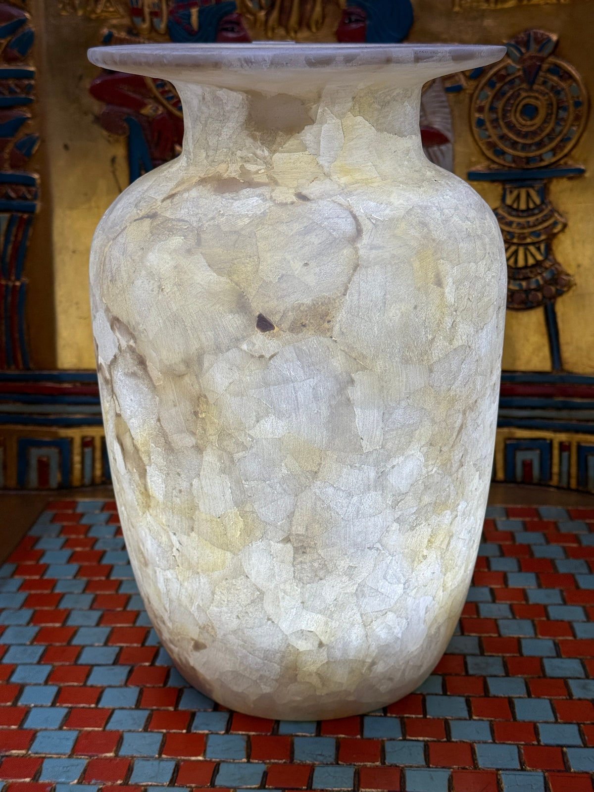 Tall ivory and cream alabaster vase with mosaic-like patterns and a broad flared rim — illuminated view.
