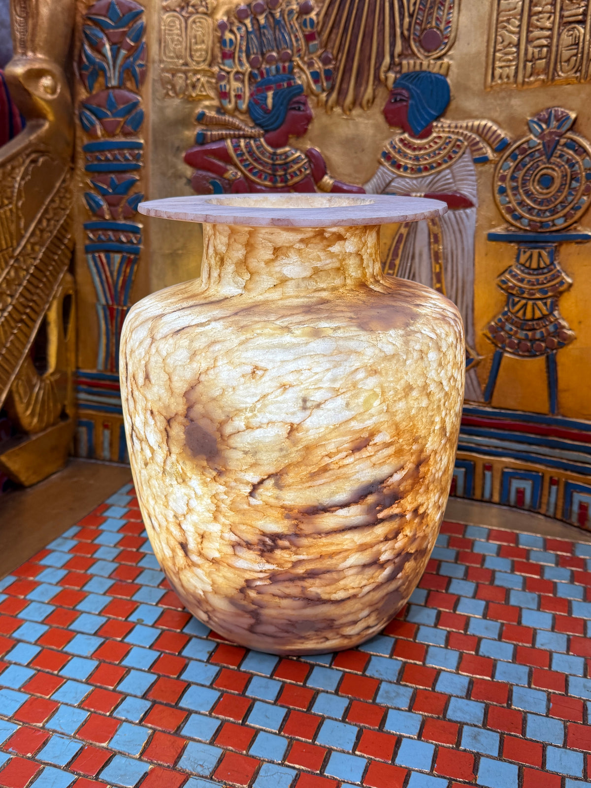 Broad alabaster vase with a low flared neck and layered honey, cream and brown veining — full view.