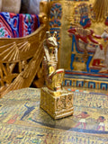 Front angled view of the gold finish Seth kneeling statue with long muzzle, upright ears and decorated square base.