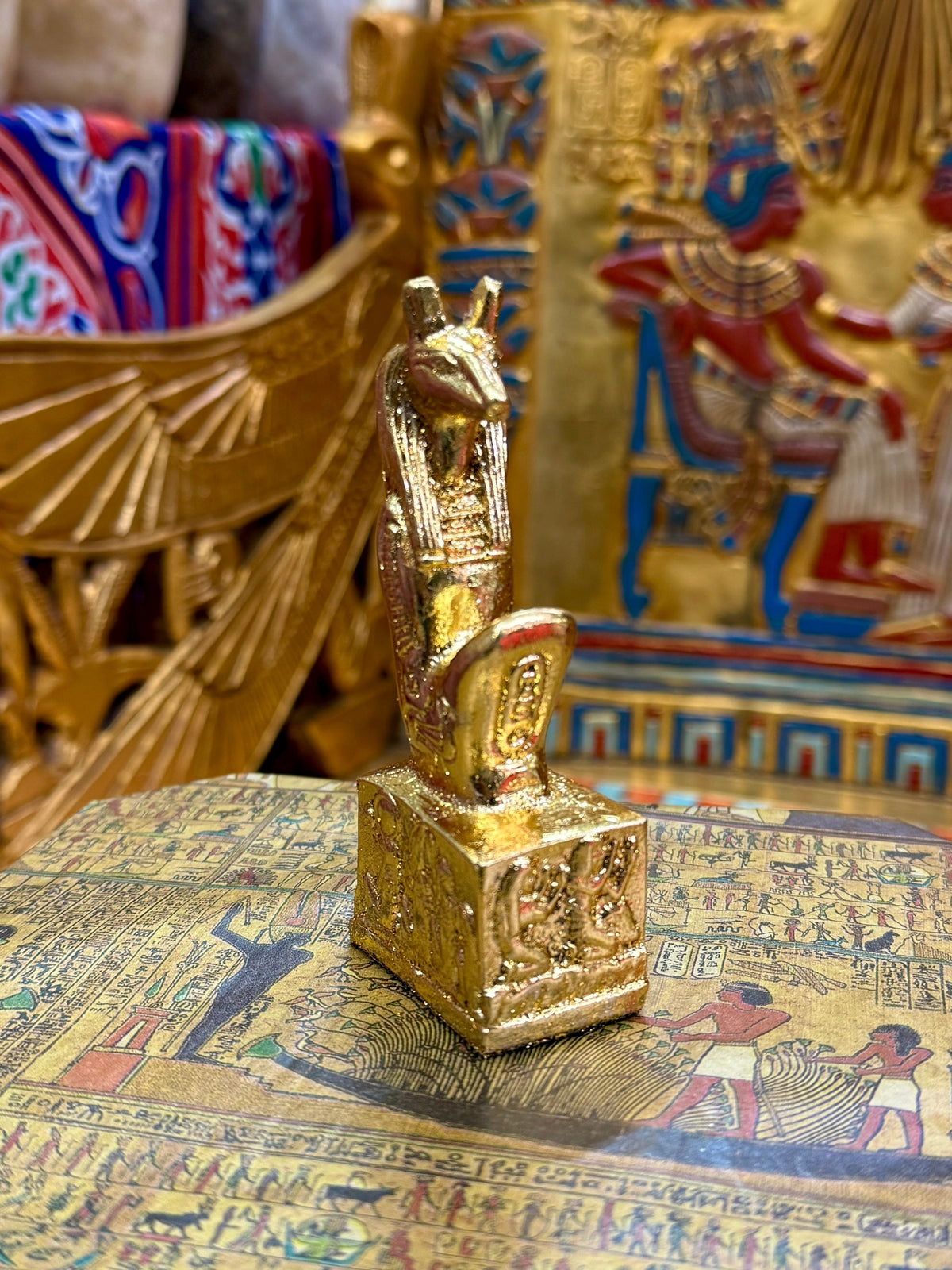 Front angled view of the gold finish Seth kneeling statue with long muzzle, upright ears and decorated square base.
