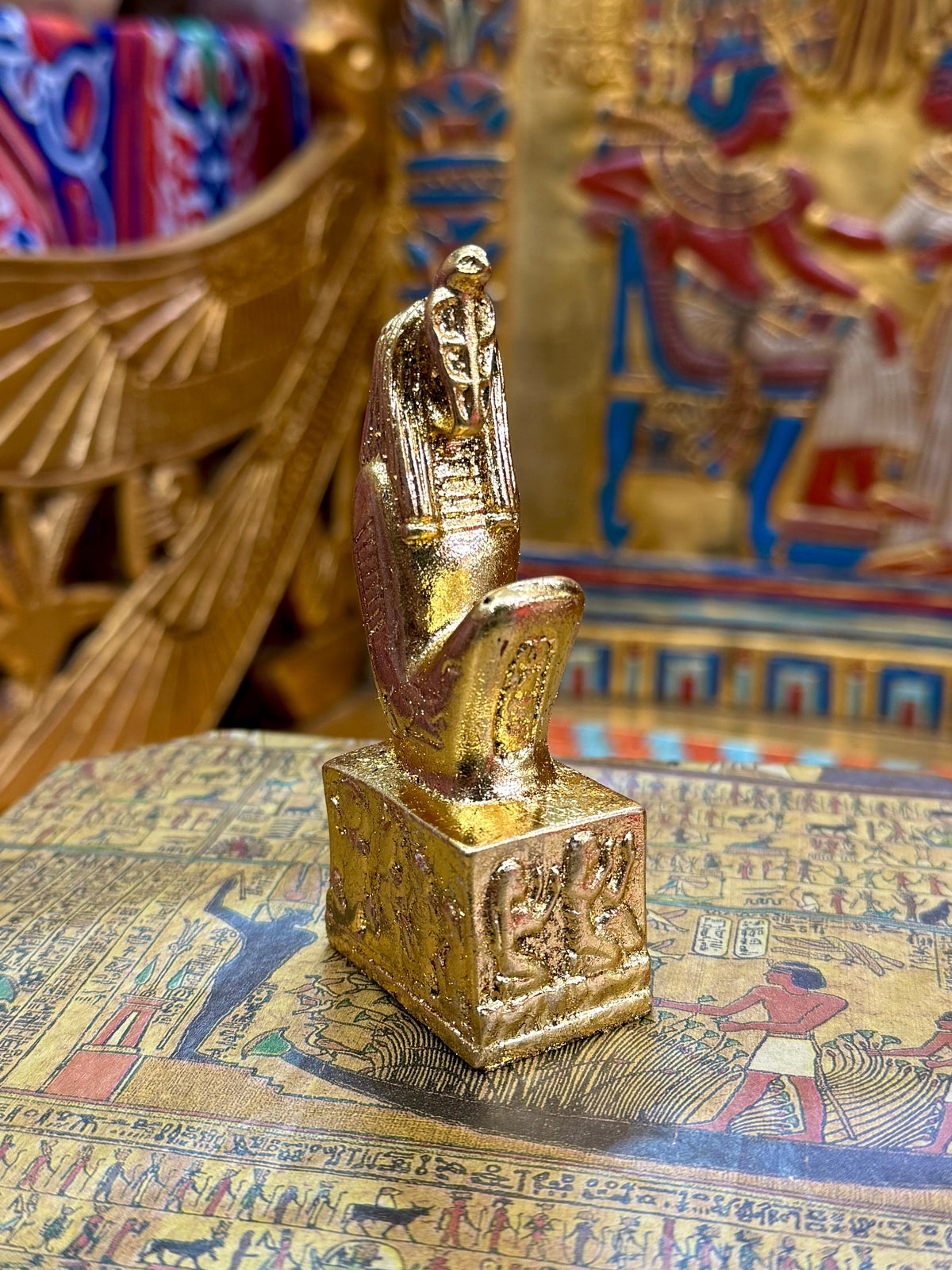 Front angled view of the gold finish Meretseger kneeling statue with cobra head and decorated square base.