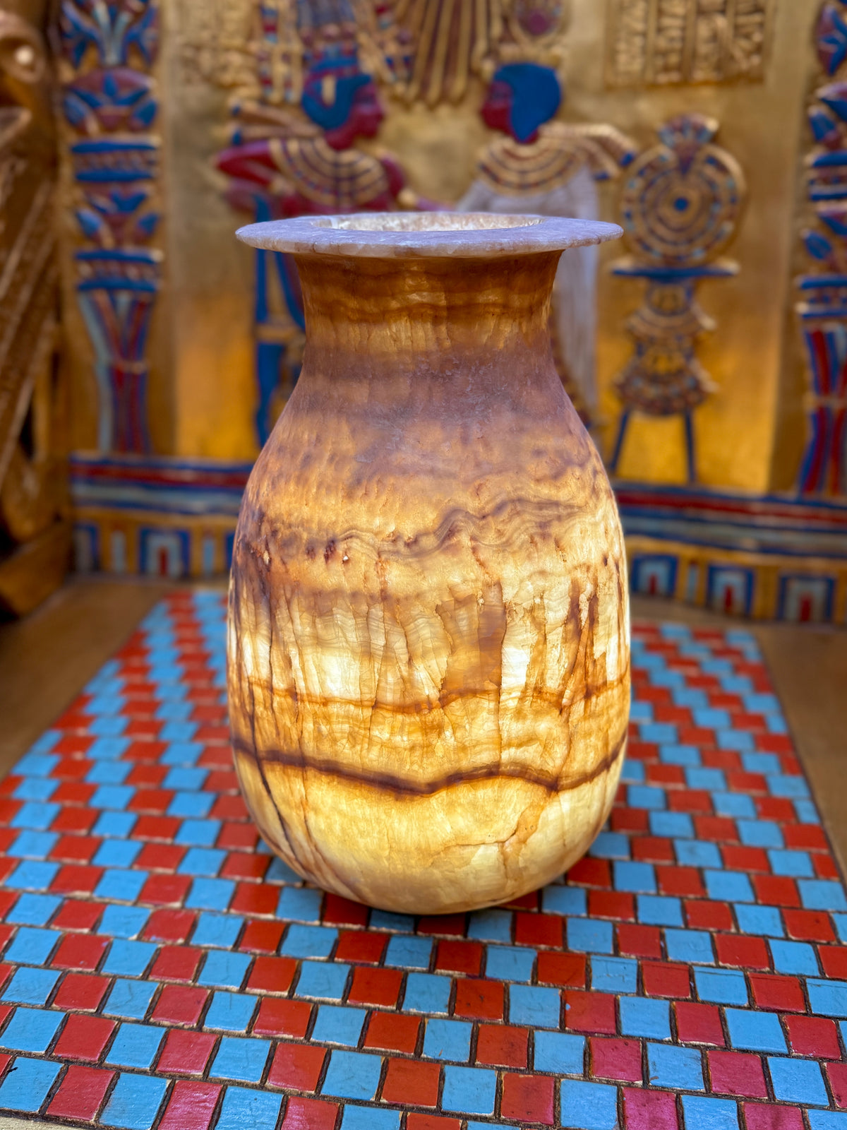Tall alabaster vase with amber-brown horizontal bands, fine vertical veins and a flared rim — full view.