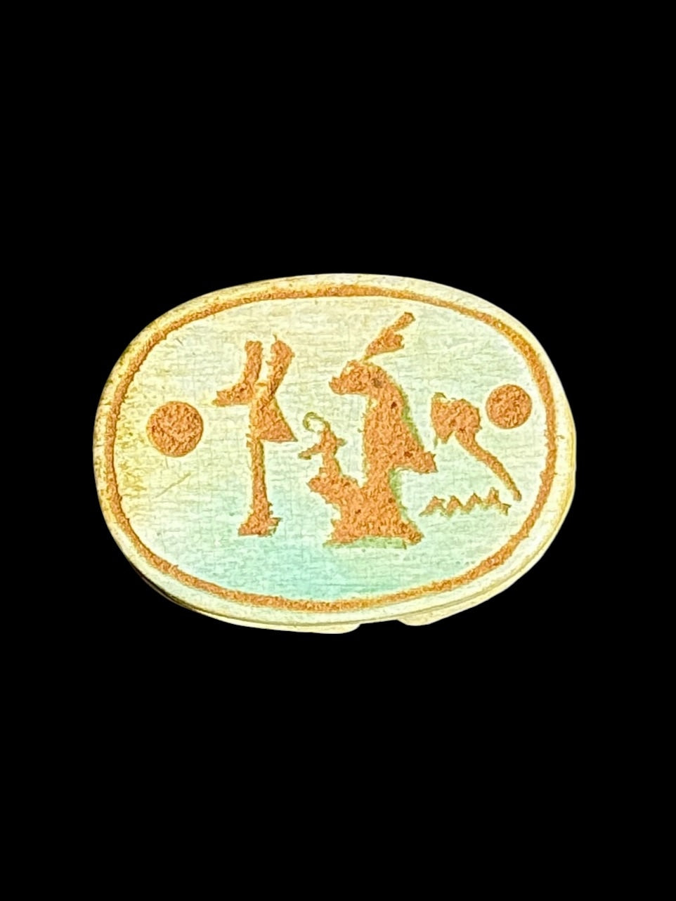 Underside of Egyptian scarab SC-098, showing pale green underside with ochre figures and circular details.