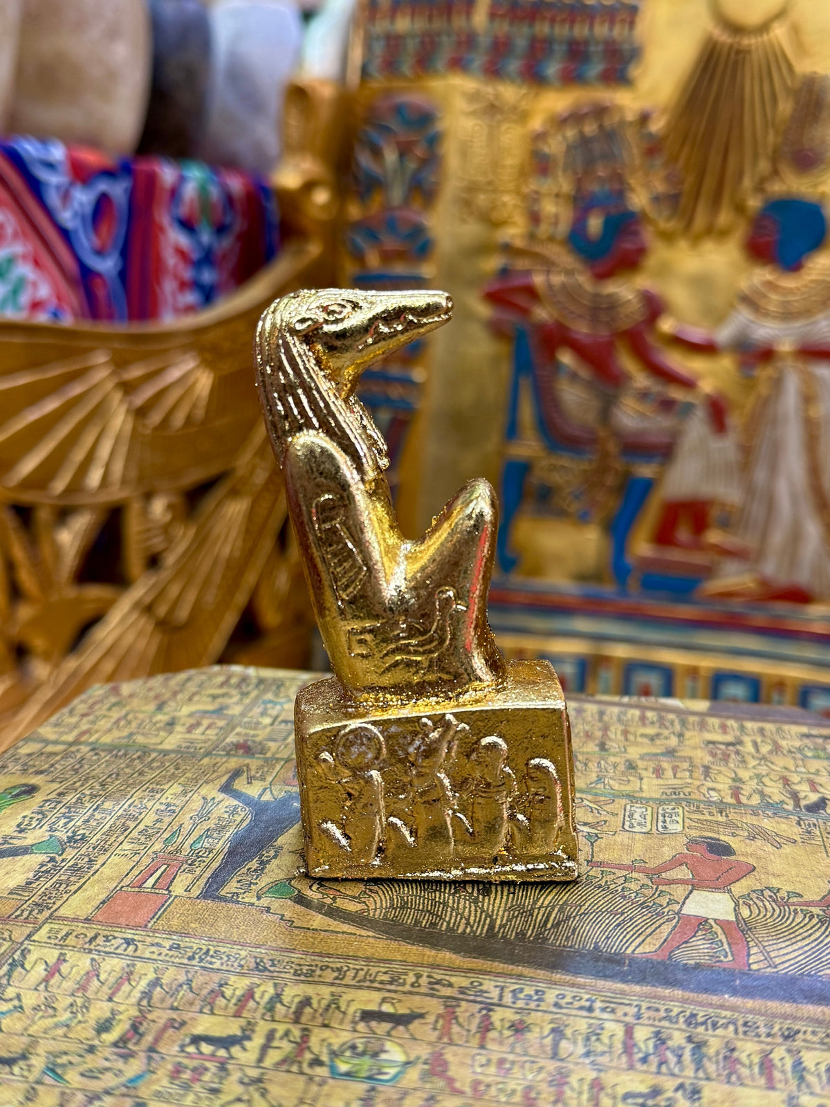Side view of the gold finish Sobek kneeling statue with crocodile head and decorated square base.