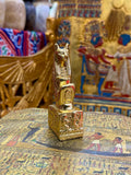 Front angled view of the gold finish Bastet kneeling statue with cat head, pointed ears and decorated square base.