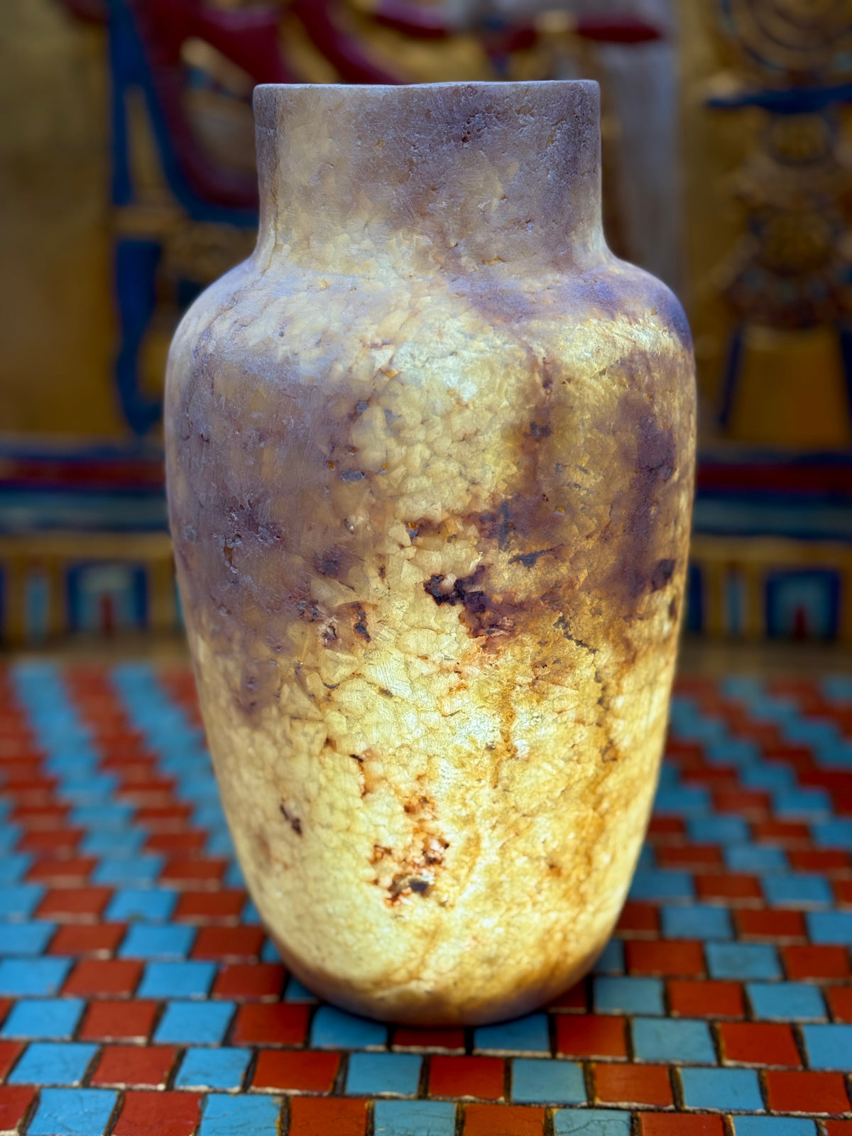 Slender smoky taupe and cream alabaster vase with rounded shoulders and a straight neck — illuminated view.