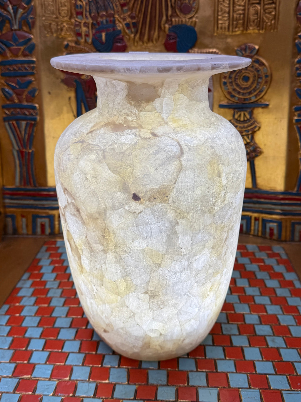 Tall ivory and cream alabaster vase with mosaic-like patterns and a broad flared rim — illuminated view.