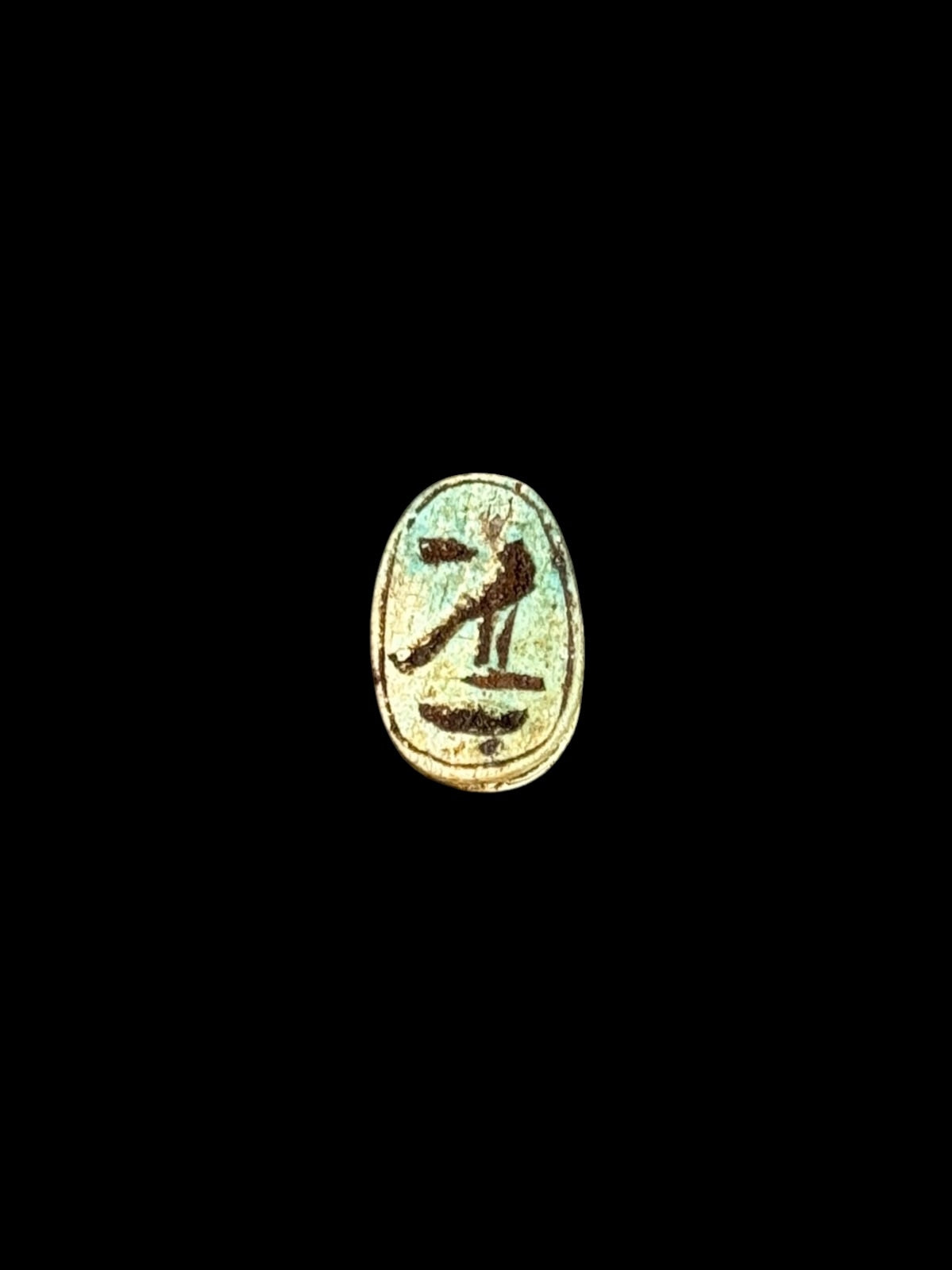 Underside of Egyptian scarab SC-056, showing pale underside with a dark bird-shaped motif and curved markings.