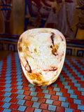 Rounded cream alabaster vase with chestnut-brown veins, curved shoulders and an open rim — full view.