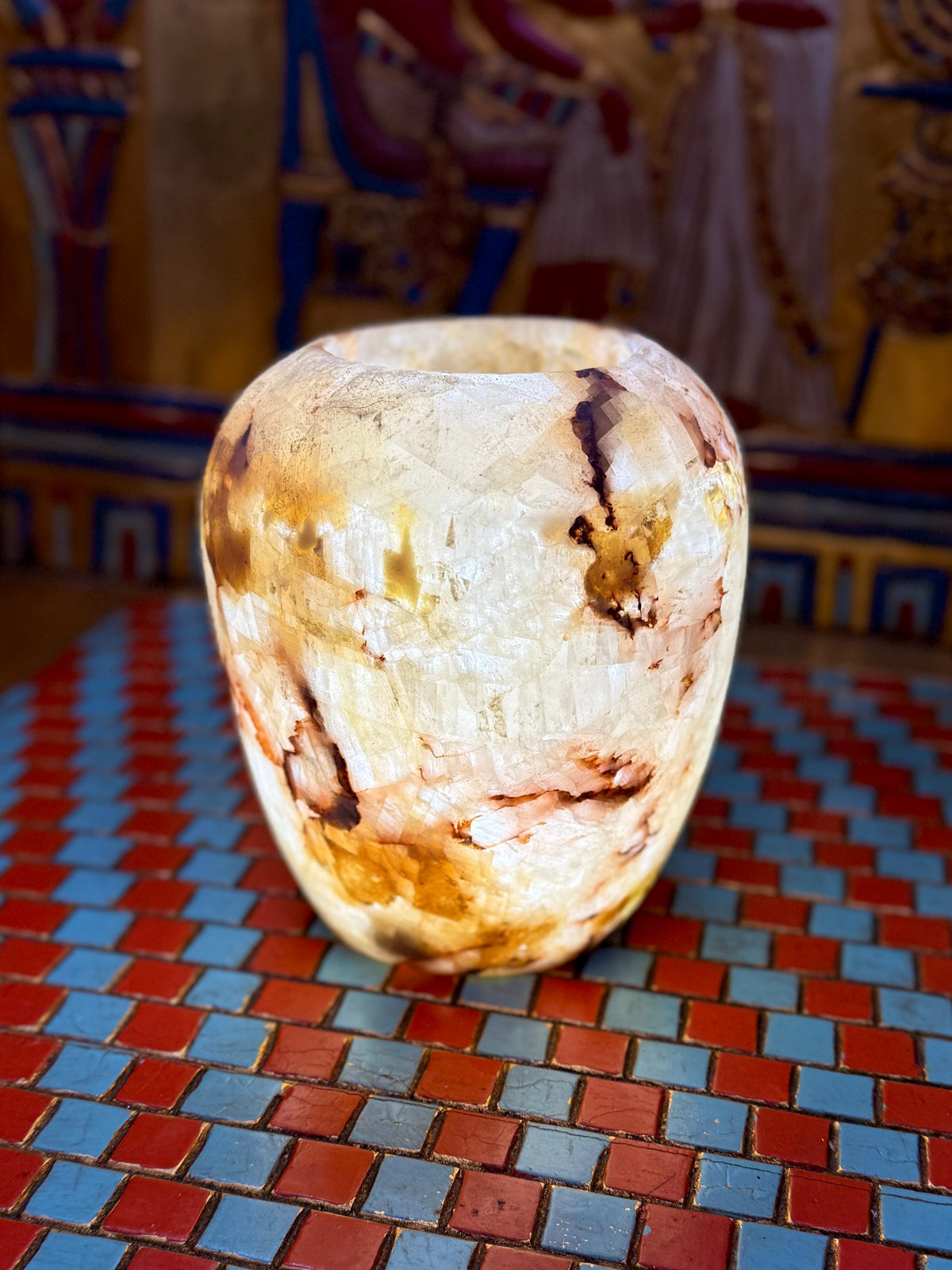 Rounded cream alabaster vase with chestnut-brown veins, curved shoulders and an open rim — full view.