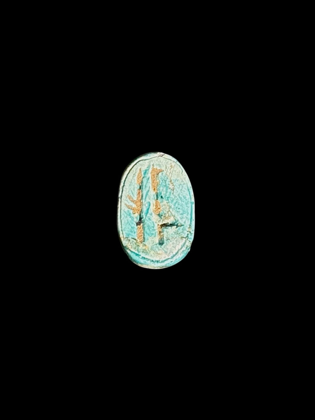 Underside of the stone scarab showing recessed markings within an oval border, with pale turquoise colouring and tan accents.